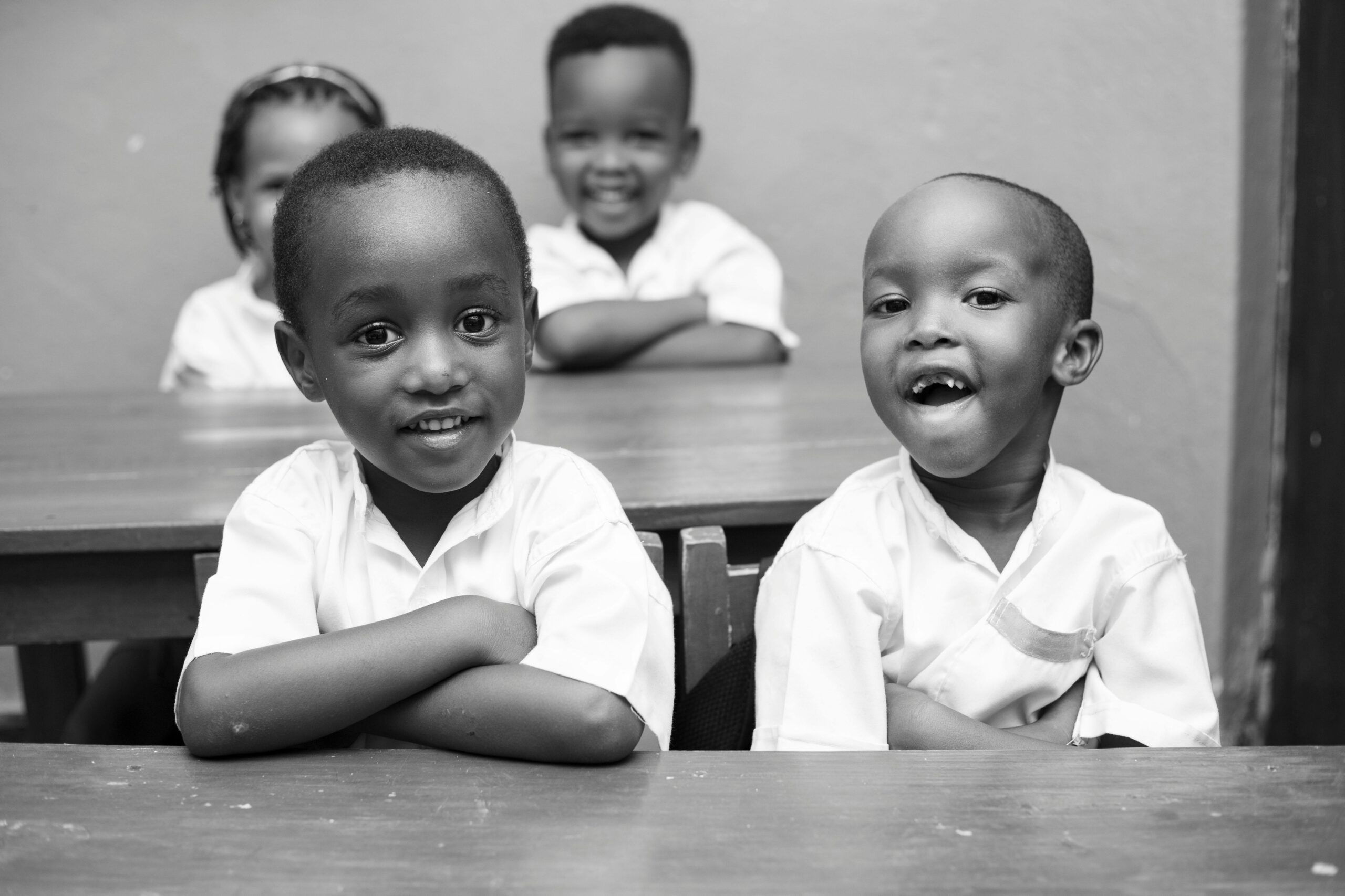 Black and white photo of joyful African children smiling in a classroom.