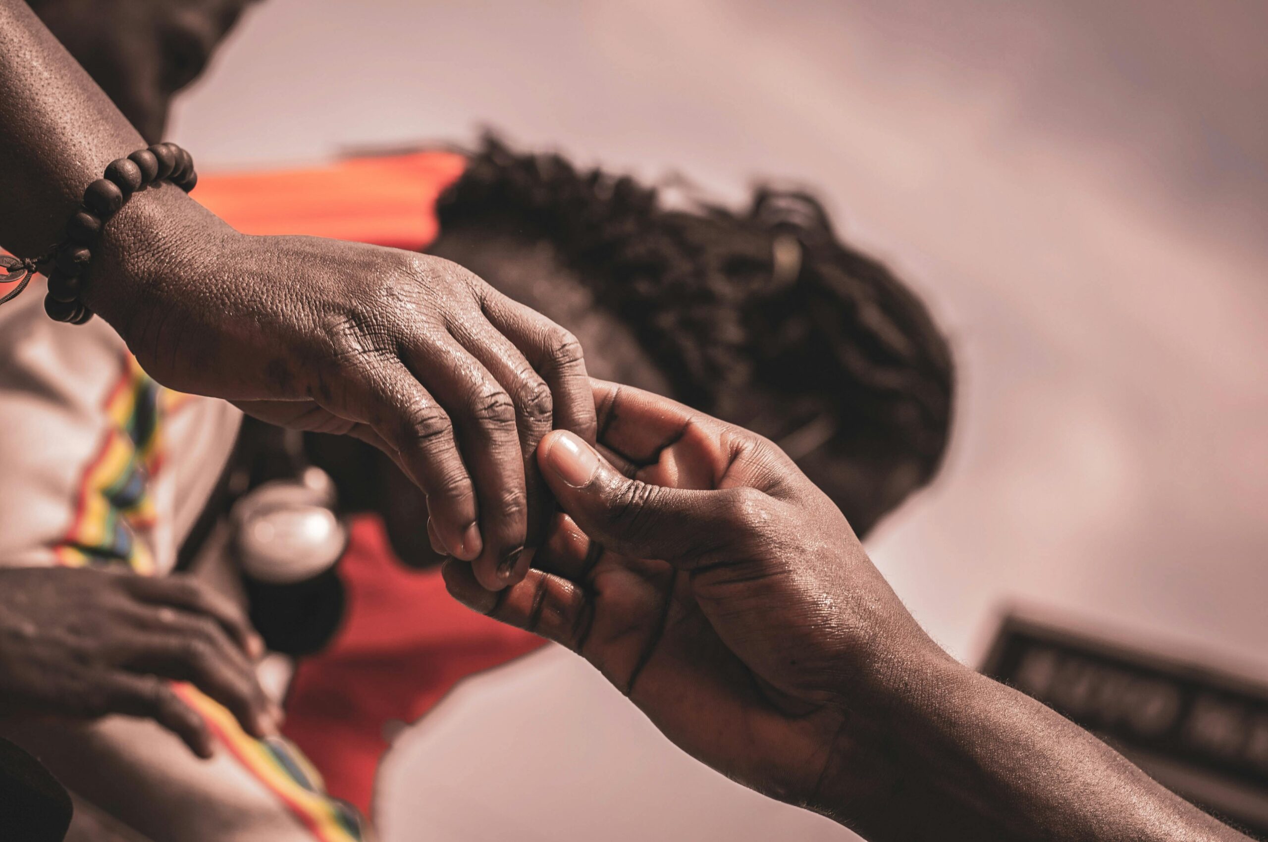 Detailed close-up of hands interacting outdoors, with a blurred background suggesting connection.
